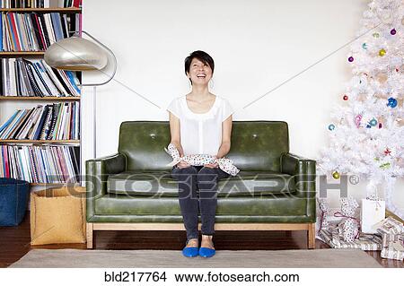 Picture - Japanese woman holding gift near Christmas tree. Fotosearch