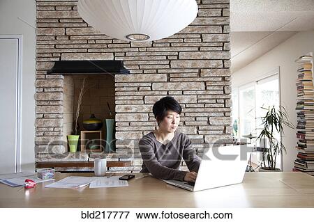 Stock Photo - Japanese woman paying bills on laptop. Fotosearch