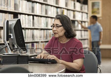 Stock Photo - Japanese woman using computer in library. Fotosearch