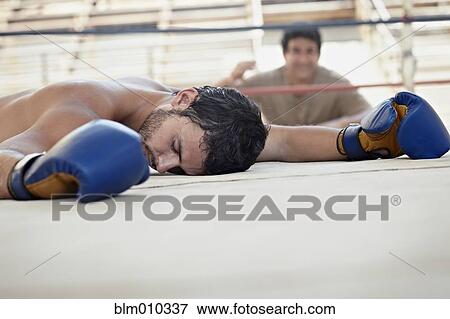 Stock Photo - Knocked-out Hispanic boxer laying on ground. Fotosearch