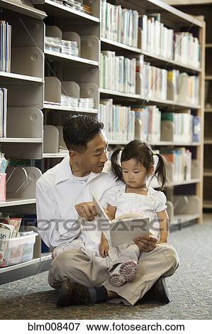 Korean father reading book to daughter in library View Large Photo Image Stock Photo - Korean father reading book to daughter in library. Fotosearch