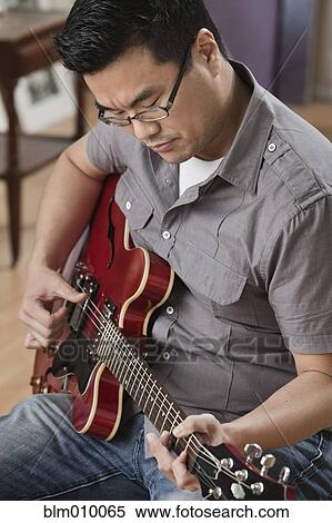 Stock Photography - Korean man playing electric guitar. Fotosearch