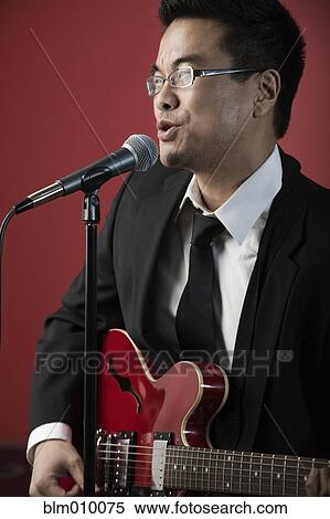 Korean man playing guitar and singing into microphone View Large Photo Image Stock Photography - Korean man playing guitar and singing into microphone. Fotosearch