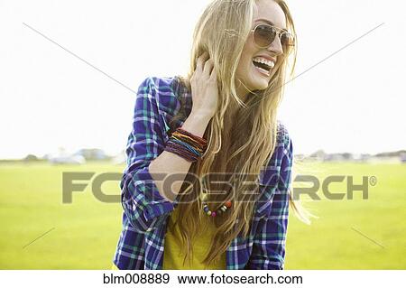 Stock Photo - Laughing Caucasian woman standing in field. Fotosearch