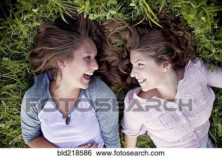 Laughing Caucasian women laying in grass View Large Photo Image Stock Photograph - Laughing Caucasian women laying in grass. Fotosearch