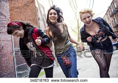 Stock Image - Laughing friends playing on city sidewalk. Fotosearch