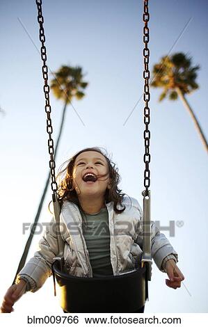 Laughing mixed race girl swinging View Large Photo Image Stock Photograph - Laughing mixed race girl swinging. Fotosearch