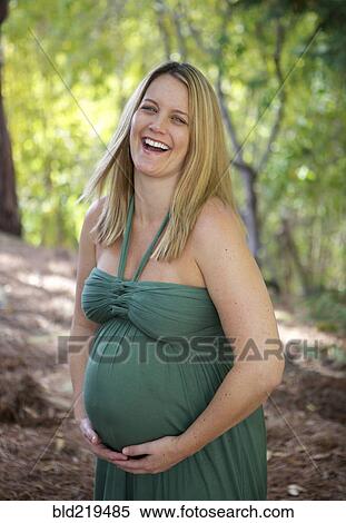 Stock Photography - Laughing pregnant woman holding belly. Fotosearch