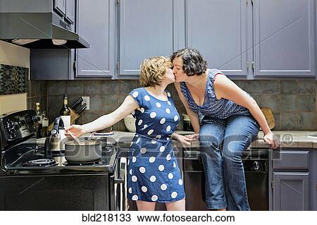 Stock Image - Lesbian couple cooking in kitchen. Fotosearch