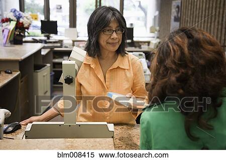Stock Photography - Librarian checking out book for patron in library. Fotosearch