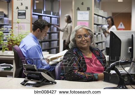 Stock Photo - Librarians sitting at desk in library. Fotosearch