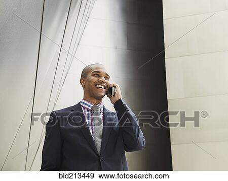 Low angle view of Black businessman talking on cell phone View Large Photo Image Stock Photo - Low angle view of Black businessman talking on cell phone. Fotosearch