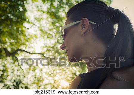 Stock Photo - Low angle view of Caucasian woman standing under tree. Fotosearch