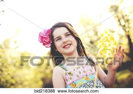 Stock Photo - Low angle view of girl playing with pinwheel in field. Fotosearch
