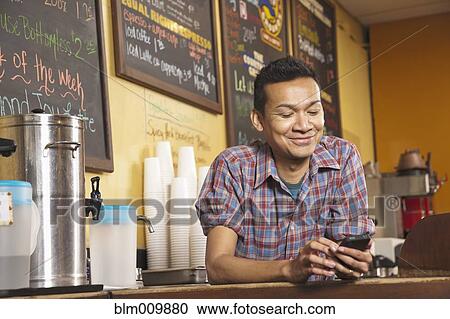 Malaysian business owner standing behind cafe counter with cell phone View Large Photo Image Stock Image - Malaysian business owner standing behind cafe counter with cell phone. Fotosearch
