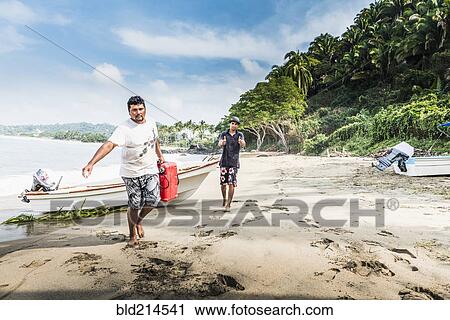Stock Image - Man carrying fuel can from boat to beach. Fotosearch