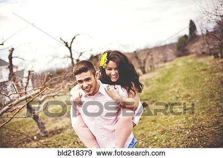 Stock Photo - Man carrying girlfriend piggyback in vineyard. Fotosearch