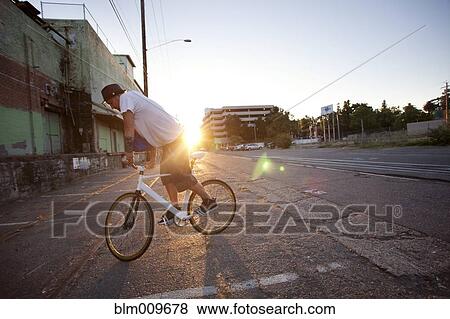 Stock Photo - Man doing stunts on bicycle on city street. Fotosearch