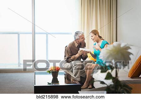 Stock Photo - Man giving wife gift on sofa. Fotosearch