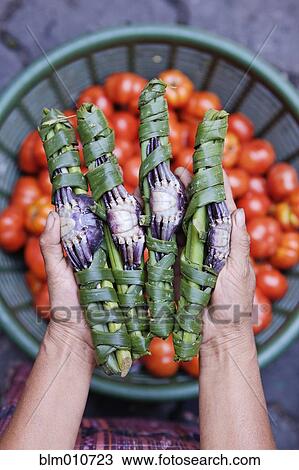 Stock Image - Man holding raw crab wrapped in leaves. Fotosearch