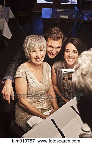 Stock Photo - Man photographing friends in restaurant. Fotosearch