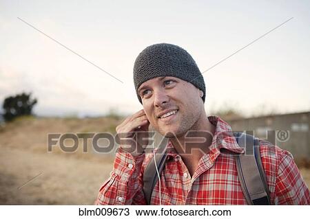 Man putting in earbuds in remote area View Large Photo Image Stock Image - Man putting in earbuds in remote area. Fotosearch