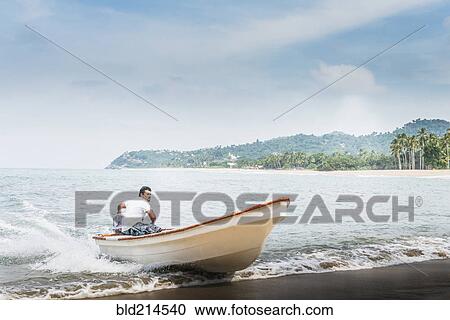 Man steering boat onto beach View Large Photo Image Stock Image - Man steering boat onto beach. Fotosearch