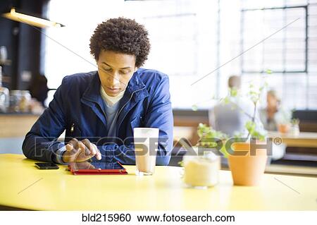 Stock Image - Man using digital tablet in cafe. Fotosearch