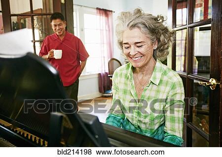Man watching wife play piano in living room View Large Photo Image Stock Photo - Man watching wife play piano in living room. Fotosearch