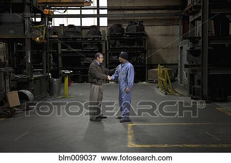 Manager and worker shaking hands in factory View Large Photo Image Stock Photo - Manager and worker shaking hands in factory. Fotosearch