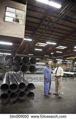 Stock Image - Manager and worker talking in factory. Fotosearch
