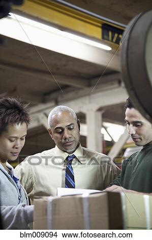 Manager and workers looking at boxes in factory View Large Photo Image Picture - Manager and workers looking at boxes in factory. Fotosearch