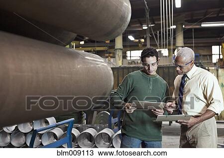 Stock Image - Manager talking to worker in factory. Fotosearch