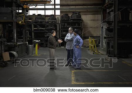 Stock Photo - Manager talking to workers in factory. Fotosearch