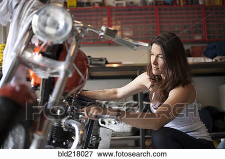 Stock Photo - Mechanic repairing motorcycle in garage. Fotosearch