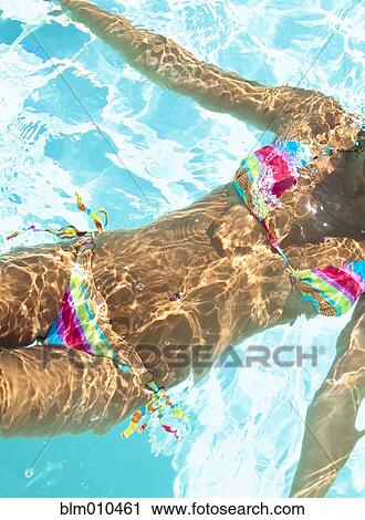 Stock Image - Midsection of mixed race woman swimming in swimming pool. Fotosearch