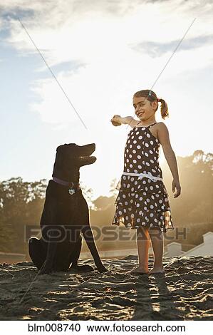Stock Image - Mixed girl playing ball with dog. Fotosearch