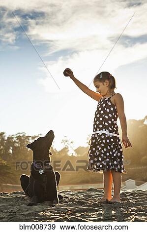 Stock Photo - Mixed girl playing ball with dog. Fotosearch
