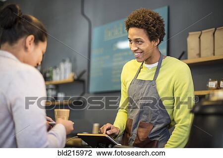 Mixed race barista assisting customer in coffee shop View Large Photo Image Stock Image - Mixed race barista assisting customer in coffee shop. Fotosearch