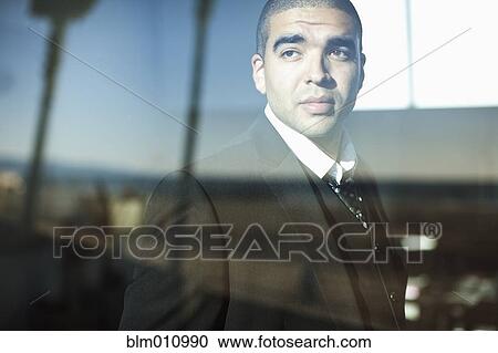 Mixed race businessman looking through window View Large Photo Image Stock Image - Mixed race businessman looking through window. Fotosearch