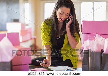 Stock Photography - Mixed race businesswoman talking on telephone in office. Fotosearch