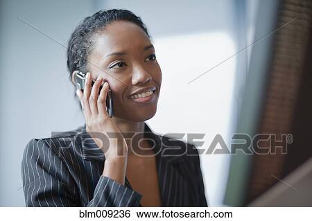 Mixed race businesswoman using cell phone at desk View Large Photo Image Stock Photograph - Mixed race businesswoman using cell phone at desk. Fotosearch
