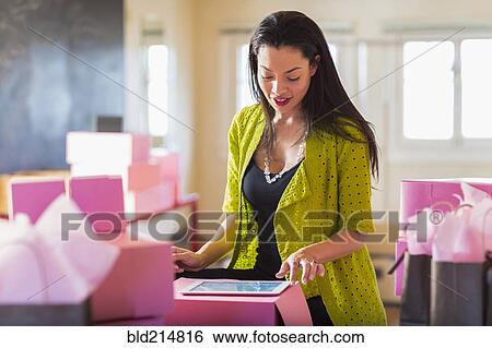 Stock Photograph - Mixed race businesswoman using digital tablet in office. Fotosearch