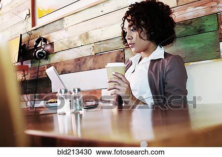 Stock Image - Mixed race businesswoman using laptop in cafe. Fotosearch
