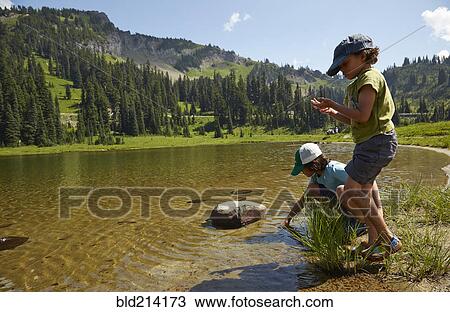 Stock Image - Mixed race children playing near remote lake. Fotosearch