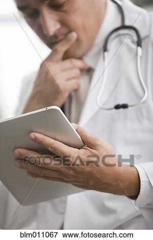 Stock Photo - Mixed race doctor using digital tablet. Fotosearch
