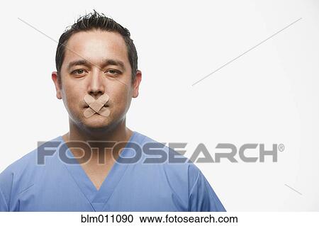 Stock Image - Mixed race doctor with bandages over his mouth. Fotosearch