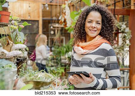 Mixed race employee using digital tablet in plant nursery View Large Photo Image Stock Image - Mixed race employee using digital tablet in plant nursery. Fotosearch