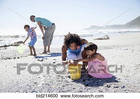 Stock Image - Mixed race family playing on beach. Fotosearch