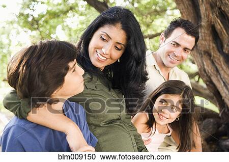 Mixed race family sitting on large tree branch View Large Photo Image Stock Image - Mixed race family sitting on large tree branch. Fotosearch